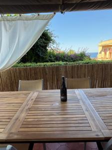 een fles wijn bovenop een houten tafel bij Terrace Garden Apartment in Acitrezza