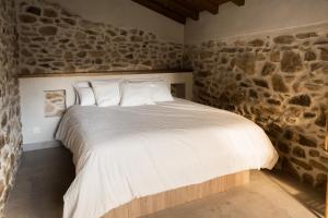 Bett in einem Zimmer mit einer Steinmauer in der Unterkunft El Corral de Cayetana in Valdemierque + 15 Fotos