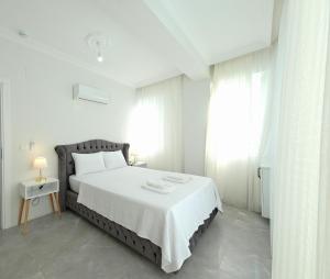 a white bedroom with a large bed and a window at The Dalaman Suites & Pansiyon Dalaman Airport 10 km in Dalaman