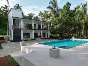 a house with a swimming pool in front of it at GroveStay in Chakkarakkal