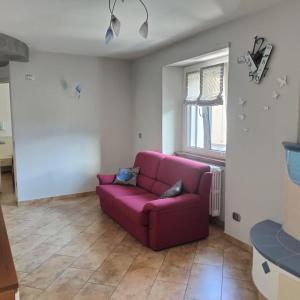 a living room with a purple couch and a window at Appartamento Nonna Rosa in Tirano