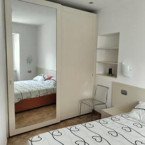 a mirror in a bedroom with a bed and a chair at Appartamento Nonna Rosa in Tirano