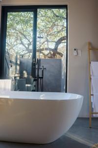 a white bath tub in a bathroom with a window at Amani Luxury Villa Marloth Park in Marloth Park