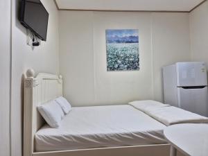 ソウルにあるSoon Guesthouseのベッド1台、冷蔵庫が備わる小さな客室です。