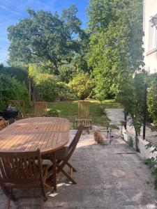 a dog sitting next to a wooden table and chairs at Between city and countryside in Maisons-Laffitte