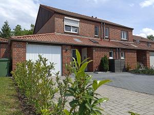 a brick house with white garage doors and a driveway at Ferienhaus-Heide in Bad Fallingbostel