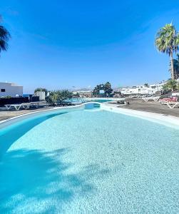 a swimming pool with blue water and palm trees at Tabaiba Place in Tías