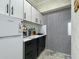 a kitchen with white cabinets and black appliances at Minar Luxrury 2BR Apartment - near Old City in Bukhara