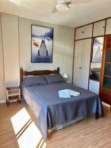 a bedroom with a bed with a picture on the wall at Apartamento completo no Centro de Nova Friburgo in Nova Friburgo