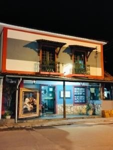 Un edificio con dos ventanas y un cuadro delante. en Pousada Vila Inconfidentes - Centro Historico, en Tiradentes