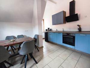 a kitchen with a wooden table and blue cabinets at Ferienwohnung zur Silbertanne in Ilsenburg