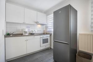 Una cocina con gabinetes blancos y un refrigerador de acero inoxidable. en Ferienwohnung Heide II, en Walsrode