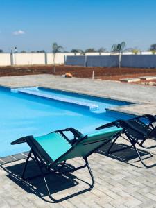 two lawn chairs sitting next to a swimming pool at KGADITSE ROAD LODGE in Moletlane +7 photos