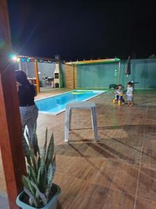 a woman and two children standing in front of a swimming pool at Chácara Baruk in Iranduba
