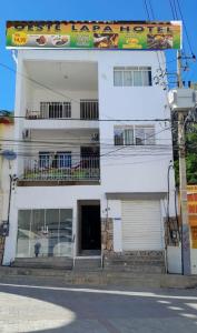 a white building with a door and a balcony at Oeste Lapa Hotel in Bom Jesus da Lapa