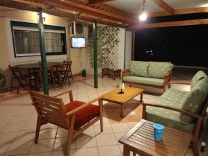 a living room with chairs and tables and a tv at Bratis House in Vartholomio