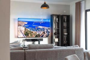 a living room with a couch and a tv on the wall at Top Location-2BR Seafront & Steps from Ferry by Arco Collection in Sliema