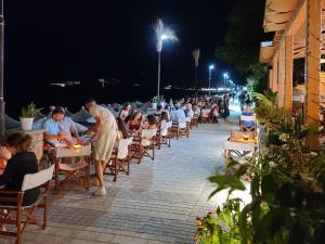 a group of people sitting at tables on a patio at night at Sunset Boulevard Beach Hotel in Qeparo