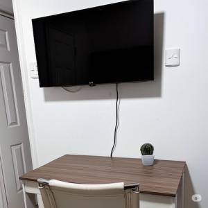 a television hanging on a wall with a wooden table at Brisa rent a home in Tocopilla