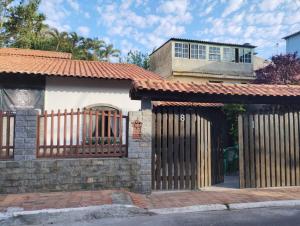 a house with a gate and a building at Suítes e café Recanto da Árvore in Arraial do Cabo