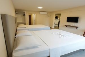une chambre avec deux lits et une télévision dans l'établissement Ilusion Flat -Natal, à Natal