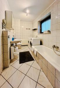 a bathroom with a tub and a washing machine at Ins Scholze große und kleine Ferienwohnungen in Albersbach in Rimbach