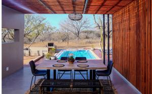 a dining room with a table and a swimming pool at Amani Luxury Villa Marloth Park in Marloth Park
