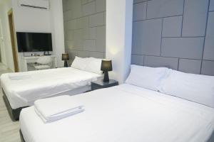 two white beds in a room with a tv at Comfy Studio 3 by Ong Realty in Singapore +3 photos
