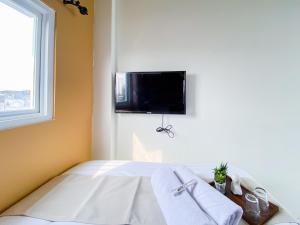 a bedroom with a bed with towels and a tv on the wall at Behomy Yume Residence in Jakarta