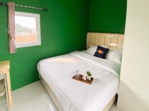 a green bedroom with a bed with a tray on it at Behomy Yume Residence in Jakarta +6 photos