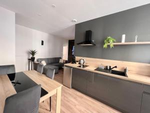 a kitchen and living room with a couch and a table at AppartNuit in Le Creusot