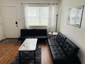 ein Wohnzimmer mit einer schwarzen Couch und einem Tisch in der Unterkunft DukeHaven near Northlake, Uptown, Route to Airport in Charlotte + 28 Fotos