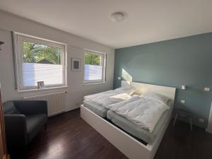 a bedroom with a bed and a chair and two windows at Johannisbeere in Raeren