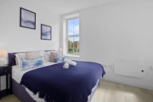 a bedroom with a bed with a blue blanket and a window at Modern Apartment, Free Parking, Smart TV, Sofa Bed in Bedford