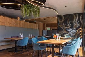 a restaurant with wooden tables and blue chairs at Hotel Acherl in Achenkirch