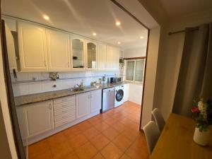a kitchen with white cabinets and a washer and dryer at Sweet home in Entroncamento