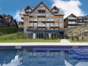 a large house with a swimming pool in front of it at Stone Suite Zakopane in Zakopane