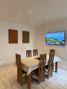 a dining room with a table and chairs and a flat screen tv at Spacious John York House & Parking in Doncaster
