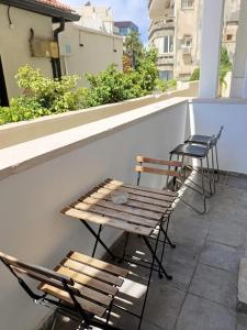 two chairs and a wooden bench on a balcony at My Lovely Apt in Tel Aviv