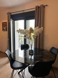 a glass dining room table with chairs and a vase with flowers at Apartman Pervan Large in Čapljina