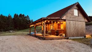 a small cabin with a deck in a field at Dobra Wola Dobra Chata - domek z balią w naturze in Dobra Wola