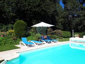 two chairs and an umbrella next to a swimming pool at Château Picol entre Futuroscope et Châteaux de la Loire in Lencloître