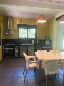 eine Küche mit einem Tisch und weißen Stühlen in der Unterkunft Increible casa Quinta en Ing Maschwitz in Maquinista Savio + 35 Fotos