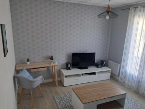 a living room with a television and a table at Maison à 50m de la plage in Gâvres