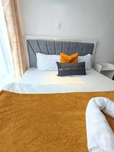 a bed with a blue headboard and orange pillows on it at Kiambu cozy studio in Kiambu