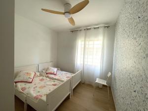 a white bedroom with a bed and a ceiling fan at Villa con barbacoa para familias in Mareny Blau +27 photos