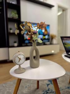 ブカレストにあるZenith Central Address Apartment with Parkingの時計の付いた花瓶のあるテーブルと時計の付いたテーブル