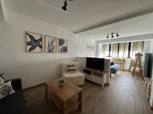 a living room with a couch and a tv in it at Apartamentos Matilda Conil - Playa in Conil de la Frontera