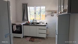 a white kitchen with a sink and a window at Meu Aconchego próximo da cidade in Itamonte