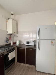 eine Küche mit Kühlschrank und Mikrowelle in der Unterkunft Depto Salta al Mar 2 in Puerto Madryn